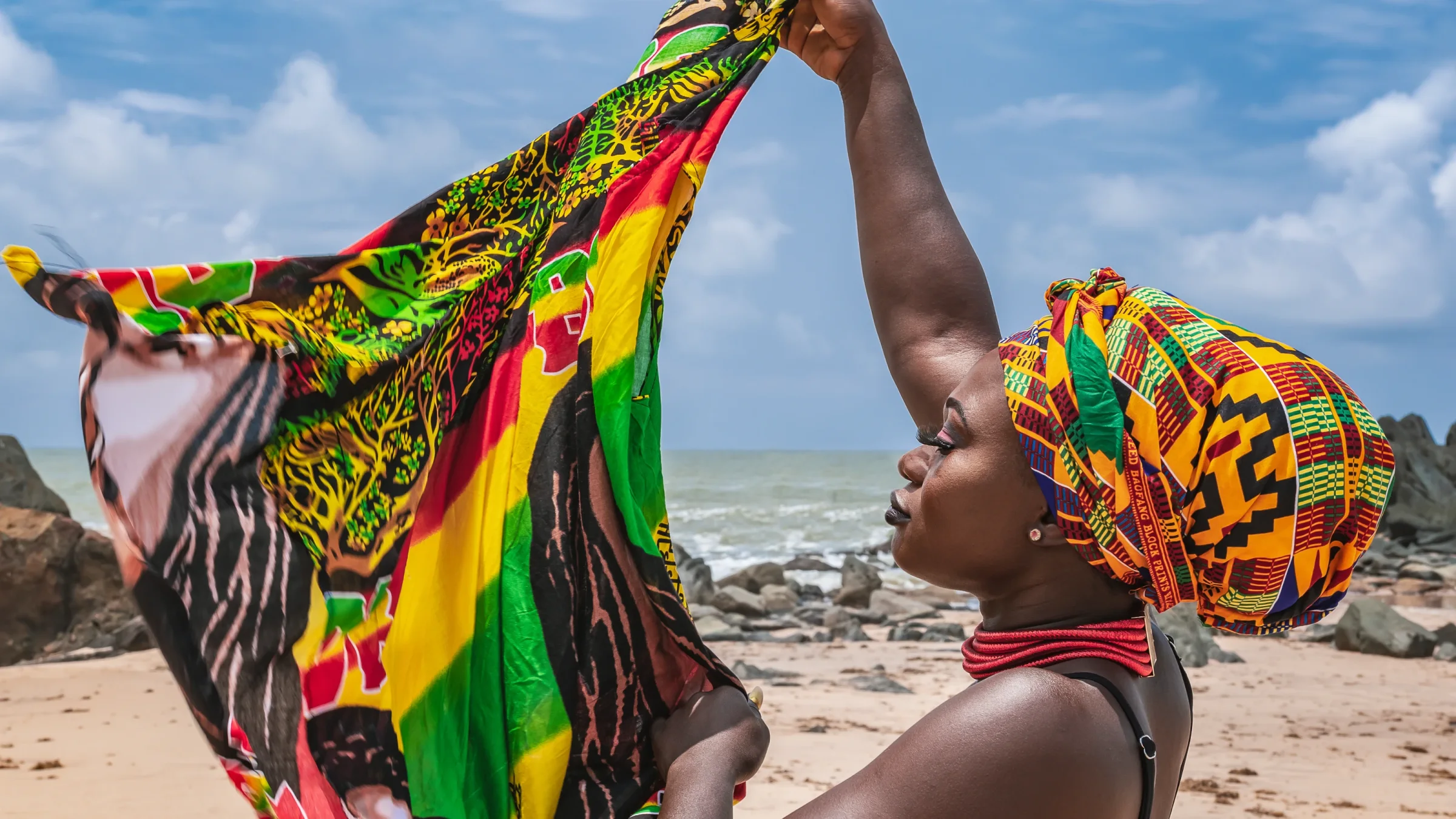 Ghanaian woman in colorful traditional styling beside the Atlantic coast